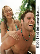 young couple enjoying a piggyback ride on a tropical beach young couple enjoying a piggyback ride on a tropical beach