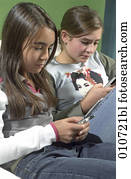 zwei mädchen, sitzen zusammen, und, schreibende, text- anzeigen, auf, bewegliche telephone