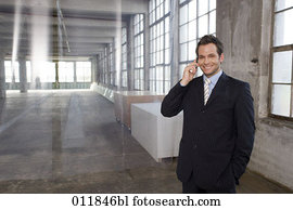 portrait of smiling businessman making a phone call in factory building portrait of smiling businessman making a phone call in factory building