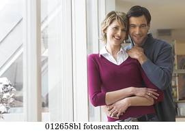 portrait of mature couple standing by the window portrait of mature couple standing by the window