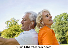 close-up of mature man and woman back to back listening to music close-up of mature man and woman back to back listening to music
