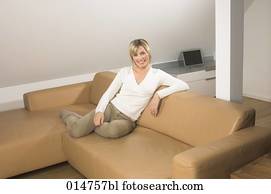 full body portrait of smiling young woman sitting on leather couch in living room full body portrait of smiling young woman sitting on leather couch in living room