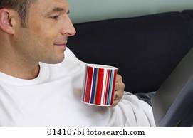 portrait of young man relaxing with book and coffee cup on sofa portrait of young man relaxing with book and coffee cup on sofa