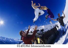 two young women in bikini tops jumping from roof of alpine hut in winter two young women in bikini tops jumping from roof of alpine hut in winter