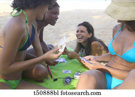 Group of young people playing cards on the beach Group of young people playing cards on the beach