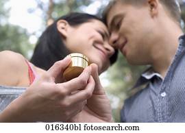 young couple looking at each other woman receiving present in golden box young couple looking at each other woman receiving present in golden box