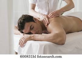 man lying on massage bench undergoing massage treatment man lying on massage bench undergoing massage treatment