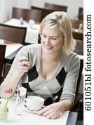 mujer joven, sentado, en, restaurante, tabla, verificar, ella, teléfono móvil, para, mensajes del texto