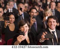 Enthusiastic theater audience videoing performance with smart phones
