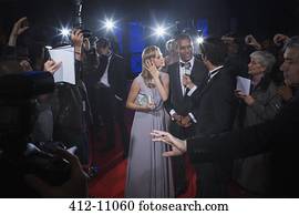 Well dressed celebrity couple being interviewed on red carpet