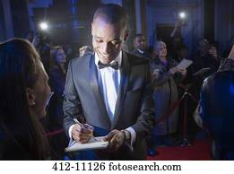 Well dressed celebrity signing autograph on red carpet
