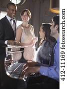 Well dressed friends playing piano in lounge