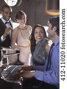 Well dressed friends playing piano in luxury nightclub