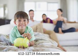 Boy with piggy bank on sofa in living room Boy with piggy bank on sofa in living room