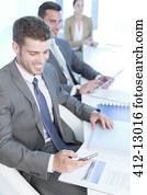 Businessman texting with cell phone in conference room