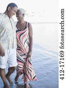 Senior couple walking barefoot on beach