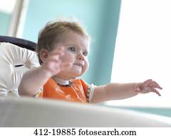 Baby girl reaching out from arm chair