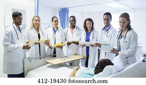 Doctor and residents examining patient in hospital room