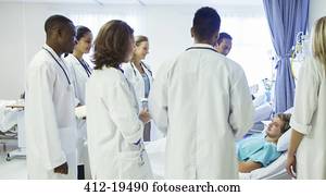 Doctor and residents examining patient in hospital room