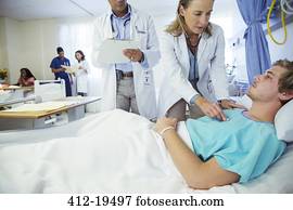 Doctors examining patient in hospital room