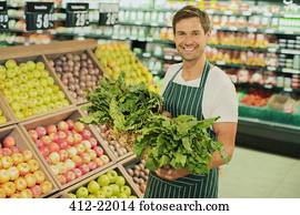 Mature grocery clerk working in organic produce aisle of grocery store