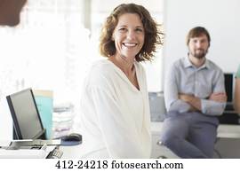 Portrait of businesswoman in office, colleague in background