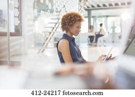 Woman using digital tablet in office, colleagues in background