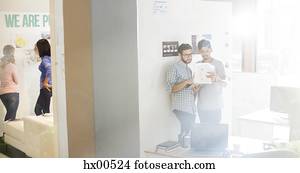 criativo, homens negócios, papelada revisando, em, ensolarado, escritório