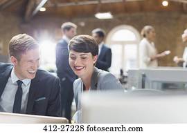 Smiling business people working at laptop in office