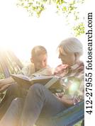 Grandmother reading to grandson in sunny hammock