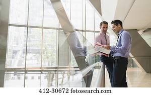 Corporate businessmen discussing paperwork in modern lobby