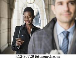 Corporate businesswoman texting with cell phone in cloister