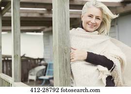 retrato, sorrindo, mulher sênior, desgastar, mantô, ligado, ventoso, alpendre