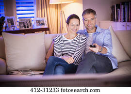 Smiling couple watching TV in living room