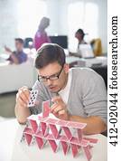 Businessman making house of cards in office