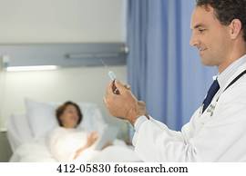 Doctor checking syringe in hospital room Doctor checking syringe in hospital room