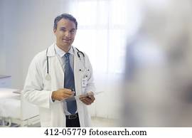 Doctor reading clipboard in hospital room Doctor reading clipboard in hospital room