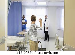 Patient waving to doctor in hospital room Patient waving to doctor in hospital room