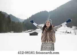 Carefree woman with arms outstretched in snowy field