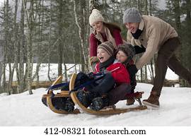 Happy family sledding in snowy woods Happy family sledding in snowy woods