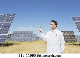 Scientist examining sphere by solar panels