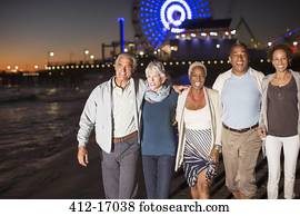 Senior friends walking on beach at night