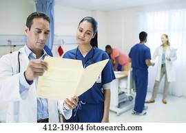 Doctor and nurse reading medical chart in hospital room Doctor and nurse reading medical chart in hospital room