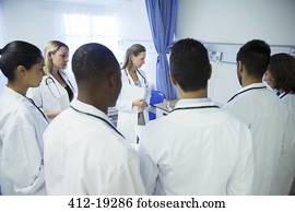 Doctor and residents examining patient in hospital room