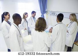 Doctor and residents examining patient in hospital room