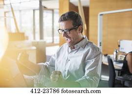 Businessman cheering at office desk