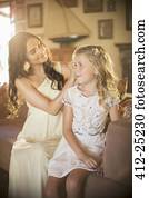 Bridesmaid helping girl with hairstyle in domestic room