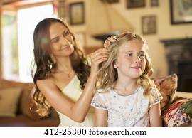 Bridesmaid helping girl with hairstyle in domestic room