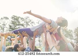 Carefree woman crowdsurfing supported by team
