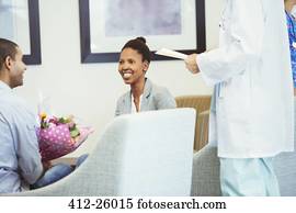 Doctor meeting with smiling couple in hospital waiting room Doctor meeting with smiling couple in hospital waiting room